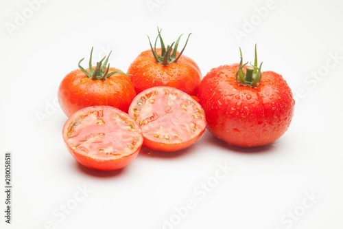 Conjunto de tomates maduros y medio tomate abierto por la mitad.