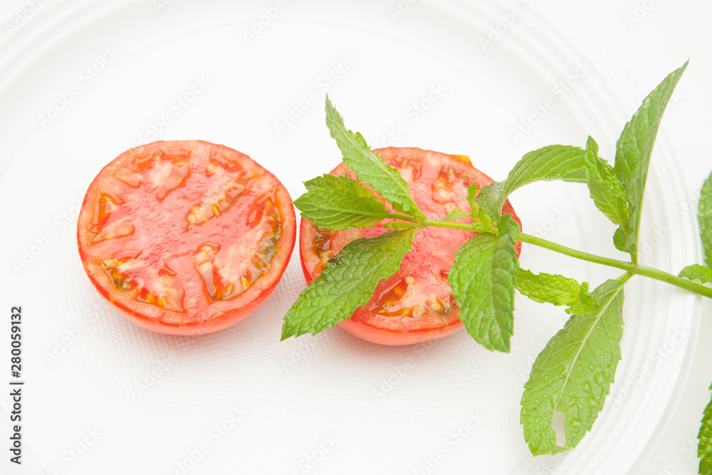 Tomate y hojas de menta sobre fondo blanco