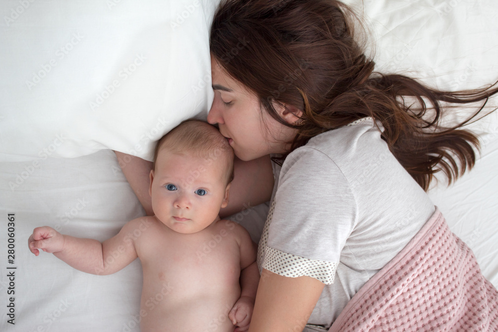 A brunette woman kisses a baby. Mom with baby closeup A brunette woman kisses a baby. Mom with baby closeup