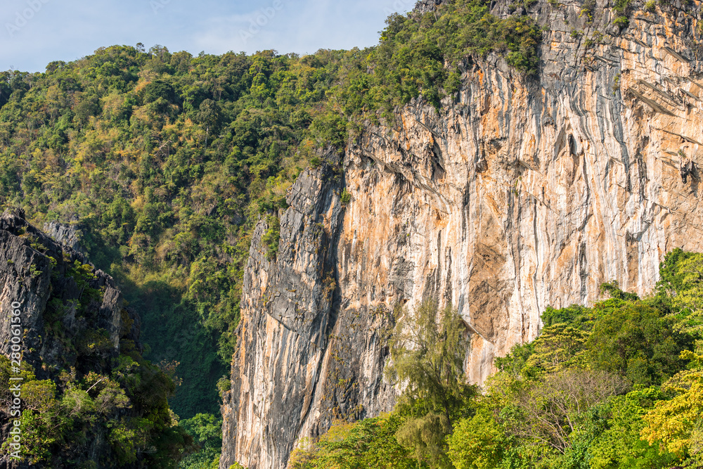 Big orange limestone cliff covered by tropical greenery