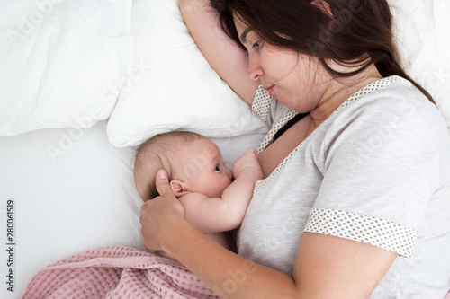 Brunette woman breastfeeds a baby. Mom with baby closeup