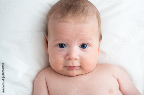 Happy baby lying on the bed. Baby on a white background close-up