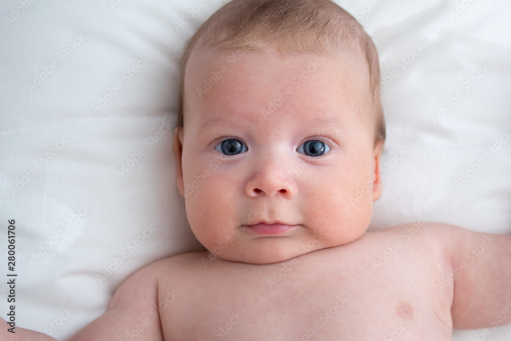 Happy baby lying on the bed. Baby on a white background close-up Happy baby lying on the bed. Baby on a white background close-up