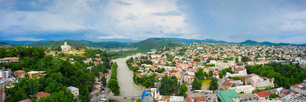 Panoramic summer view of the city of Kutaisi, Georgia. Bagrati's Cathedral and River Rioni and old houses with Red roofs. Mountains in the distance.