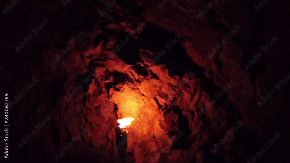 Oil torch burning inside dark natural cave making shadows on cave walls. Filmed while taking a group spring hike in slow motion hd.