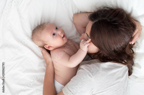 Brunette woman playing with baby. Mom hugging baby closeup