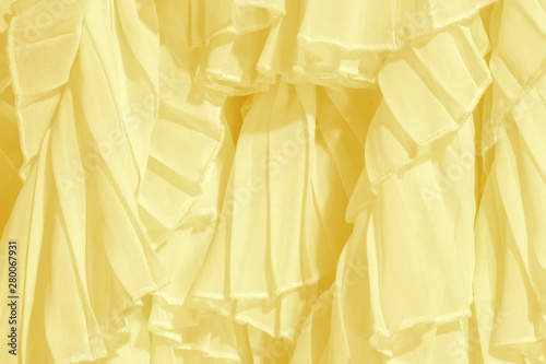 Soft pastel color chiffon fabric folds. Yellow dress with ruffles and frills. 
