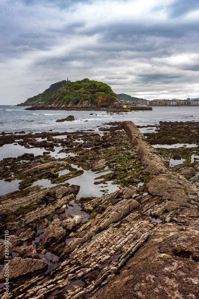 LANDSCAPE OF SEA AND ROCKS ON SHORE WITH LOW TIDE ON THE BEACH OF SAN SEBASTIAN IN BASQUE COUNTRY