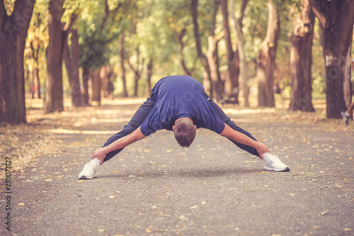 Young man doing stretching exercise in the park
