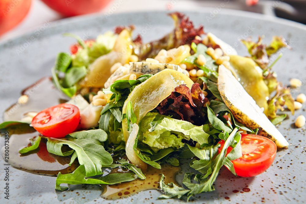 Salad with sliced pears, gorgonzola cheese, greens and pine nuts