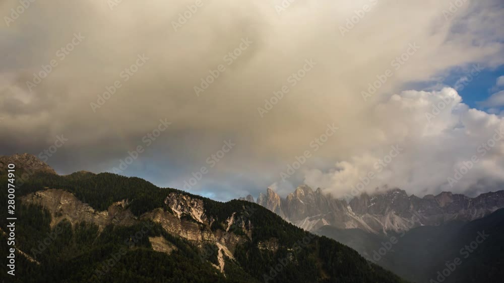 Clouds moving over Dolomites mountains with a rainbow fading in a timelapse Clouds moving over Dolomites mountains with a rainbow fading in a timelapse
