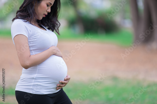 Portrait of asian Beautiful pregnant woman at the park,Thailand people,Happy woman concept,Her use hand touch her belly,Mother day concept © reewungjunerr