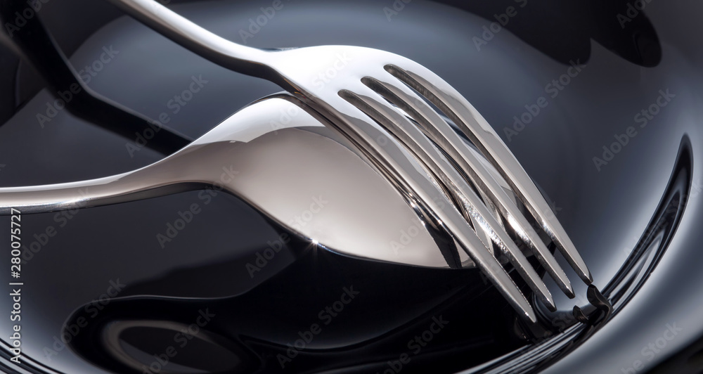 Empty plate with spoon and fork on a black background Empty plate with spoon and fork on a black background