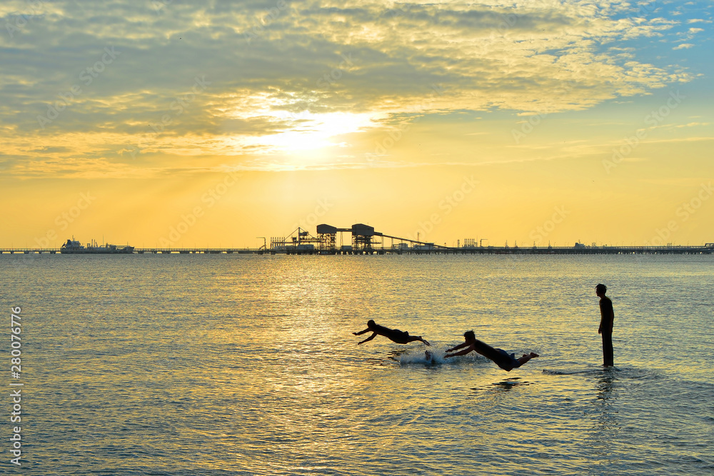 Silhouettes of young group of people swimming in ocean at sunset Silhouettes of young group of people swimming in ocean at sunset