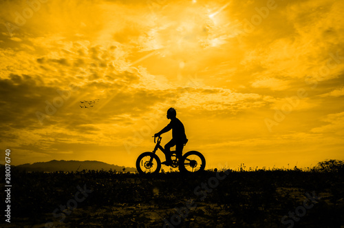 Silhouette of a boy riding a bicycle