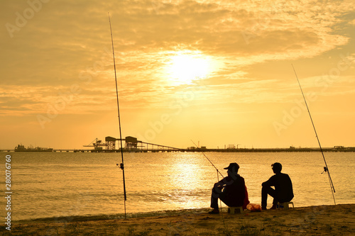 Obraz na plátne Silhouettes of fishermen at sunset