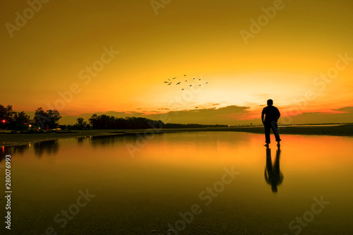 Silhouette of a men looking to the beautiful sky during golden sunset