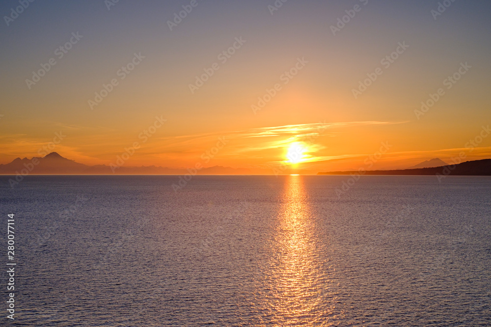 Gorgeous sunset with reflection in the Pacific ocean and beautiful mountains shown in horizon in breathtaking Alaska
