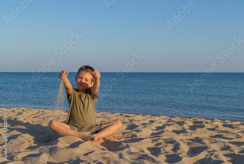 Sports child does yoga and meditates on the beach. The sandy beach is quiet and peaceful. Copy space.