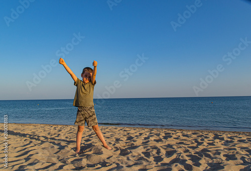 Sports child does yoga and meditates on the beach. The sandy beach is quiet and peaceful. Copy space.