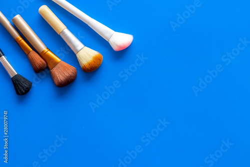 Brushes for make up on blue visagiste work desk background top view copyspace