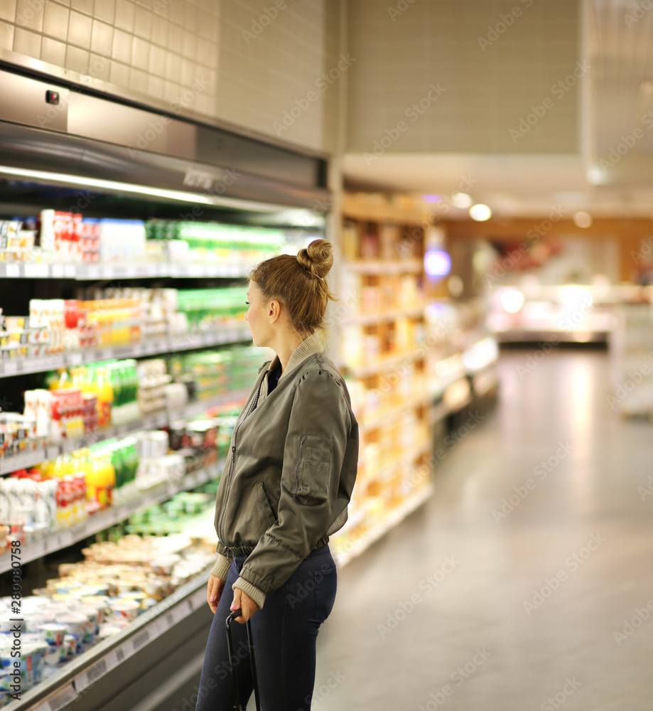 Woman  shopping in supermarket, reading product information