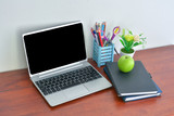 Office supplies, laptop with notebook and apple on wooden table