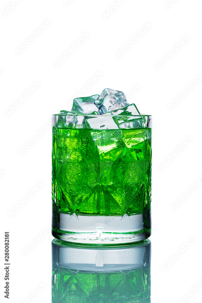 Crystal glass filled with ice and green lemonade on a white background with reflection Crystal glass filled with ice and green lemonade on a white background with reflection