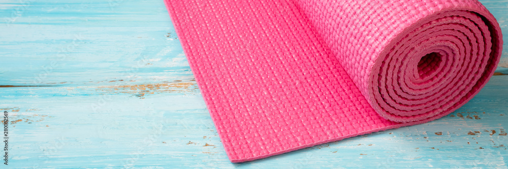 Pink yoga mat on blue wooden background. Equipment for yoga. Concept healthy lifestyle, sport and diet. Copy space Pink yoga mat on blue wooden background. Equipment for yoga. Concept healthy lifestyle, sport and diet. Copy space
