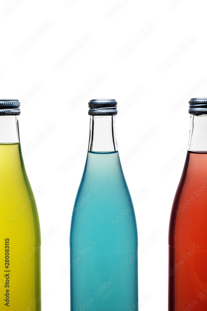 three colorful glass bottles with lemonade on white background. blue bottle whole yellow bottle and red bottle half in the frame three colorful glass bottles with lemonade on white background. blue bottle whole yellow bottle and red bottle half in the frame