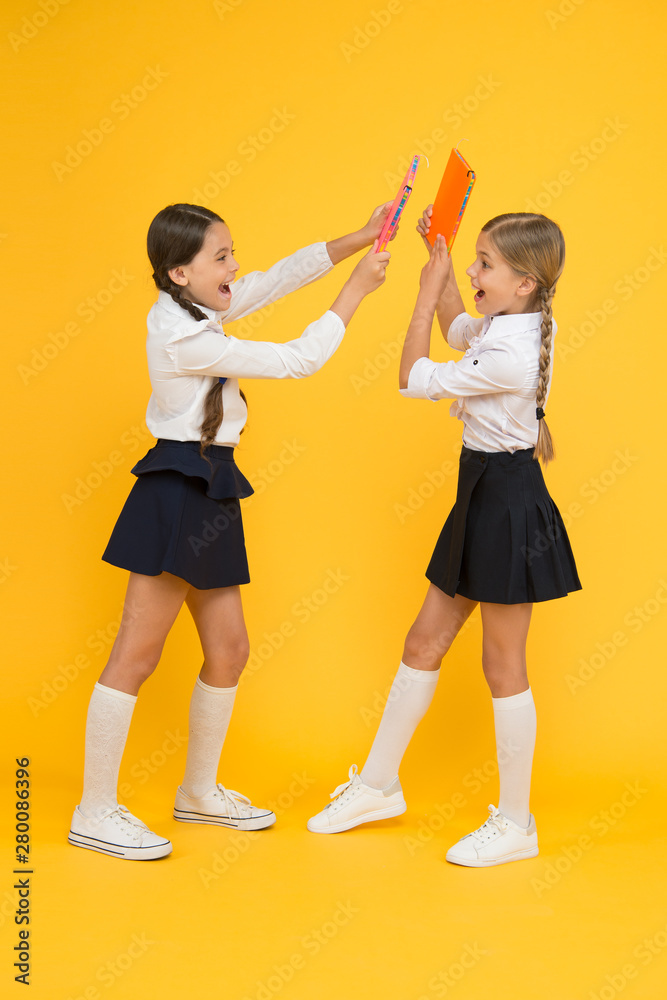 Obraz premium playfool mood. kids learning grammar. back to school. dictionary notebook. Get information. cheerful classmates with workbook. little girls in school uniform. reading story. childrens literature