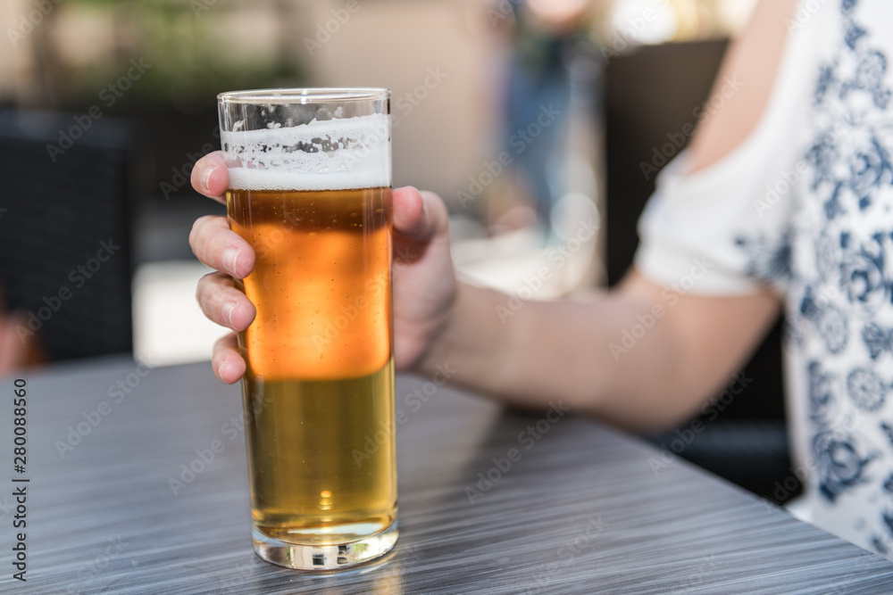 The hand of a young woman holds a glass of beer on the table of a terrace in Caceres The hand of a young woman holds a glass of beer on the table of a terrace in Caceres
