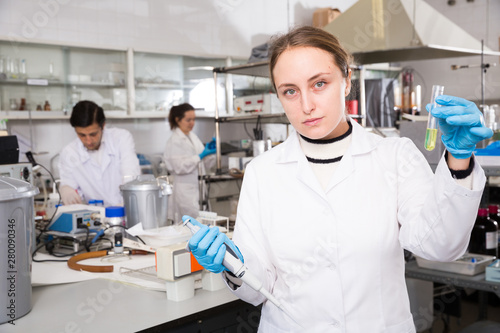 Female chemist analyzing liquid in test flasks