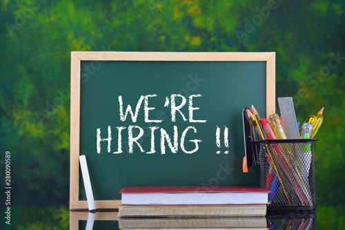 Green school chalkboard with written sentence WE'RE HIRING