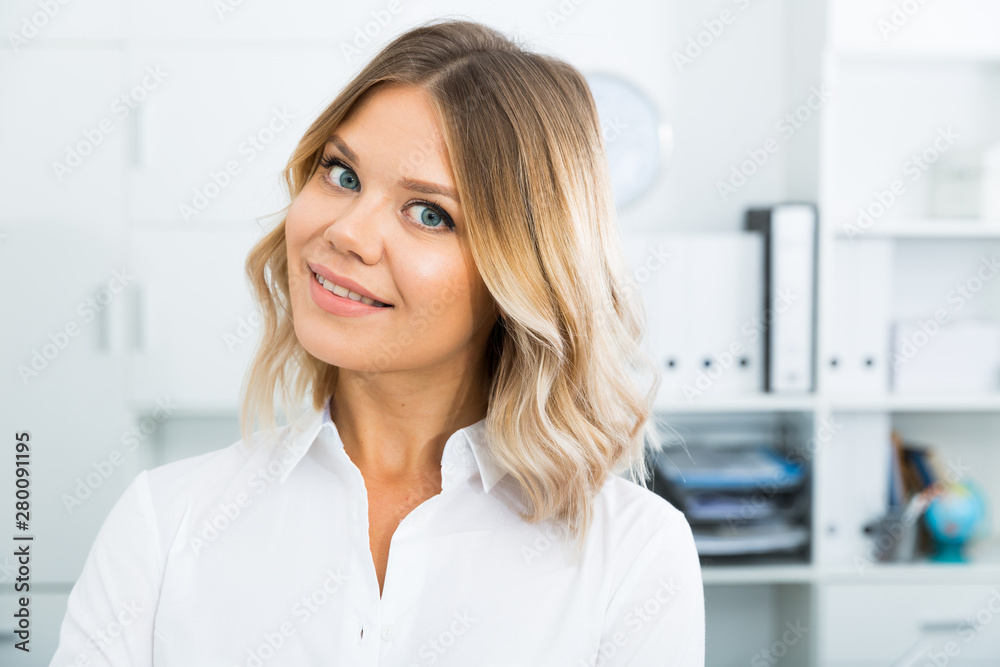 Young blonde girl in business clothes in well-lit office close-up