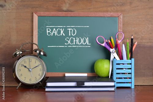 Back to school concept with books and alarm clock with chalkboard