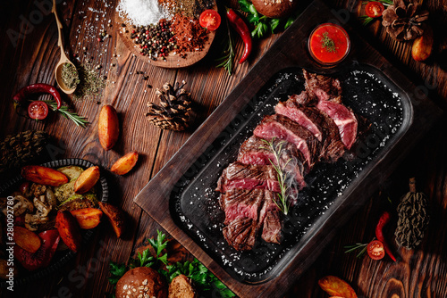 Φωτογραφία Juicy roasted veal tenderloin sliced decorated rosemary on dark board on dark wooden background in beautiful composition among vegetables and spices