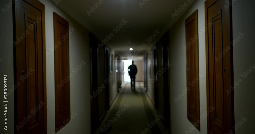 serious bald man silhouette walks along luxury hotel hall