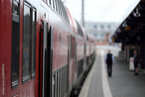 Geöffnete Tür bei einem Nahverkehrszug am Bahnsteig mit Zugbegleiter und wartendem Fahrgast - Stockfoto