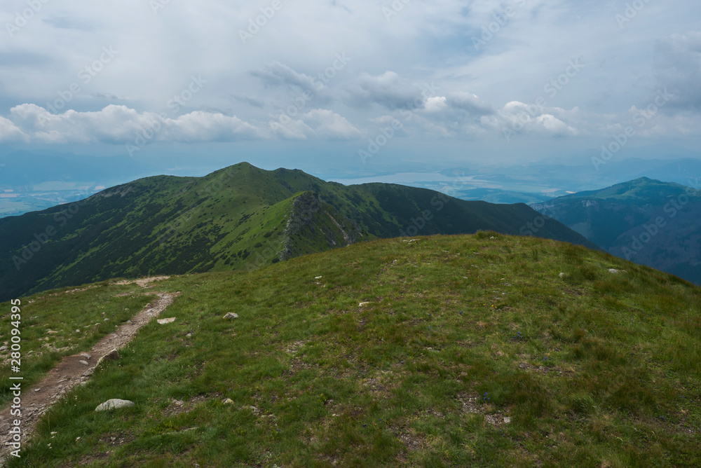 Beautiful mountain landscape of Western Tatra mountains or Rohace panorama. Sharp green grassy mountain peaks with hiking trail on ridge. Summer blue sky white clouds. Beautiful mountain landscape of Western Tatra mountains or Rohace panorama. Sharp green grassy mountain peaks with hiking trail on ridge. Summer blue sky white clouds.