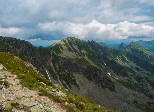 View from Banikov peak on Western Tatra mountains or Rohace panorama. Sharp green mountains - ostry rohac, placlive and volovec with hiking trail on ridge. Summer blue sky white clouds.