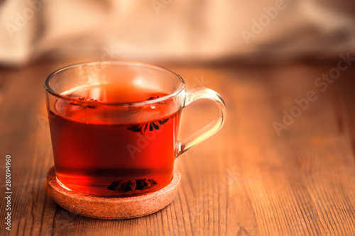 a cup of hot black tea with star anise on a wooden table