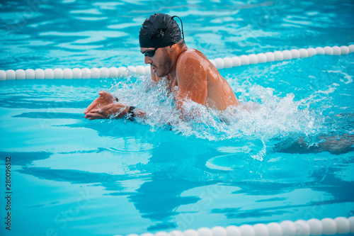 Closeup male athlete swimming breaststroke in pool during Champions. photo
