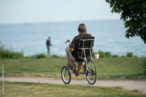 middle aged man rides a recumbent bicycle on a sunny day at the park to keep fit and stay healthy