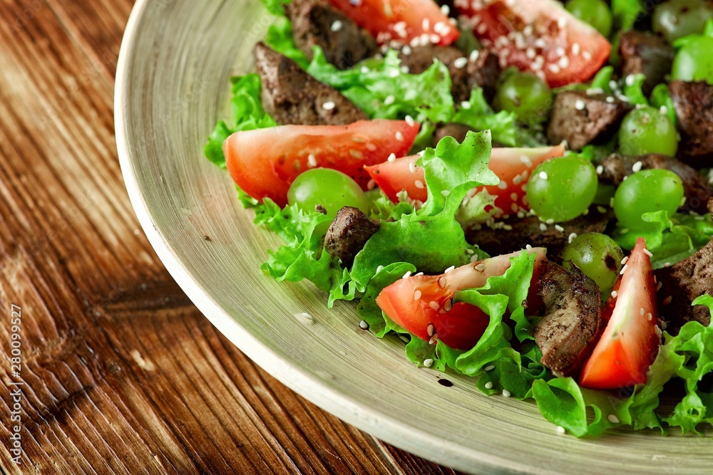 warm salad with chicken liver and grapes on a wooden table warm salad with chicken liver and grapes on a wooden table