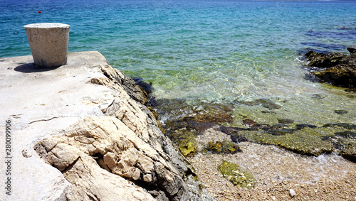 Nature background with detail of sea coastline and wild pebble beach and stone mooring bollard