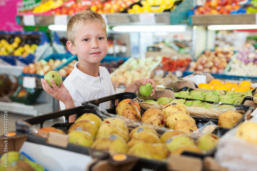 little boy choosing fresh fruits at shop