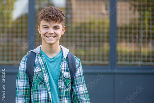 Schoolchild go to school with backpack. Cute child - teen boy with bag against the background of school. Back to school concept.
