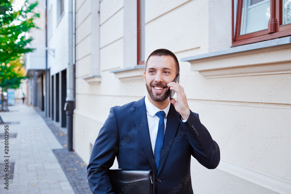 Smiling young businessman talking on phone in the city Smiling young businessman talking on phone in the city