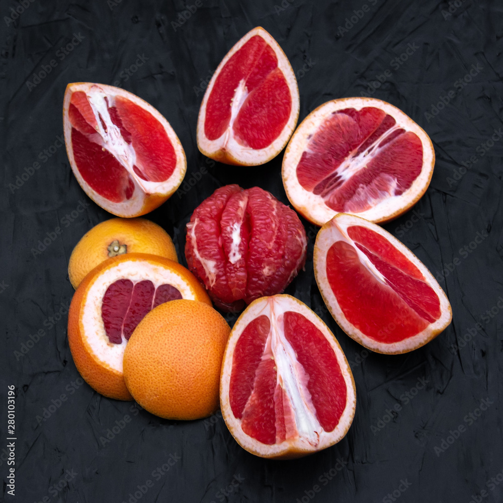 Ripe juicy cut red grapefruit slices on black wood background closeup Ripe juicy cut red grapefruit slices on black wood background closeup